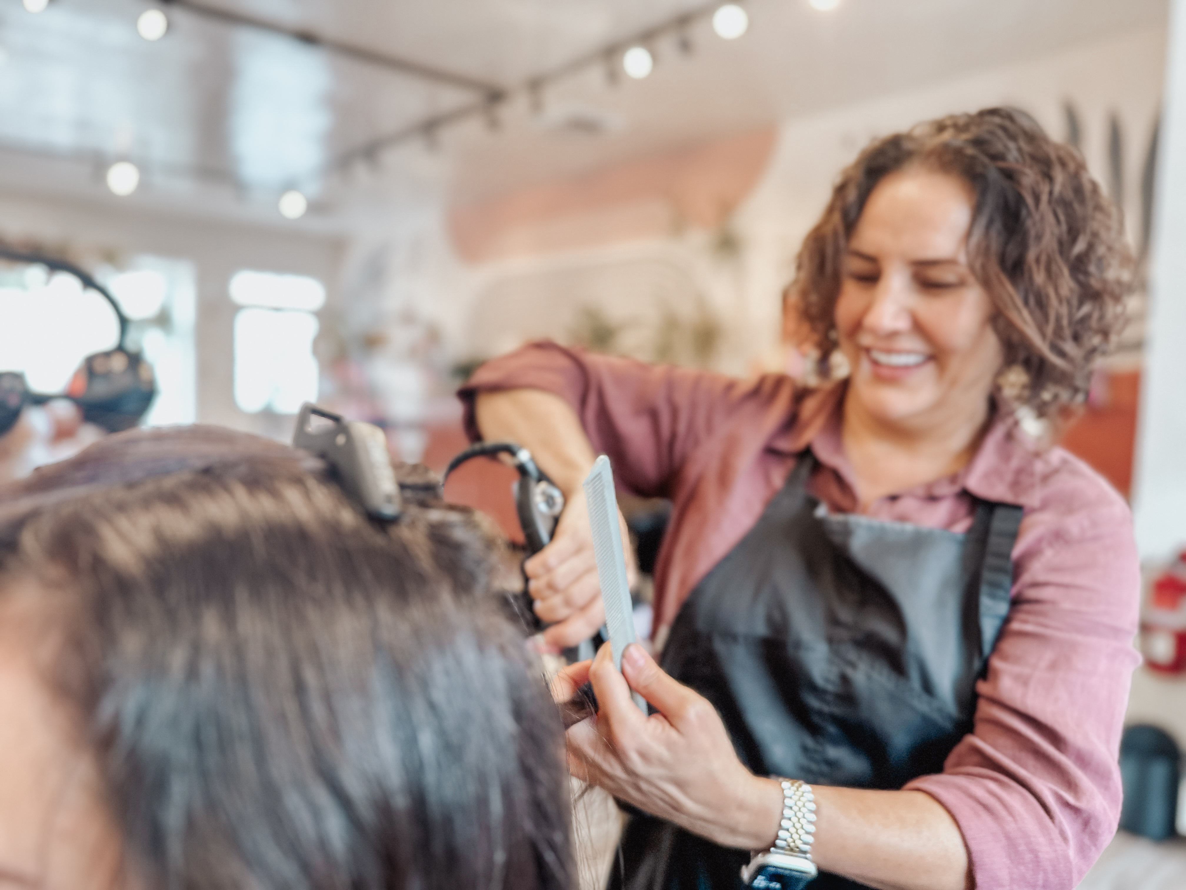 Shakufeh Sharif smiling while styling a client's hair